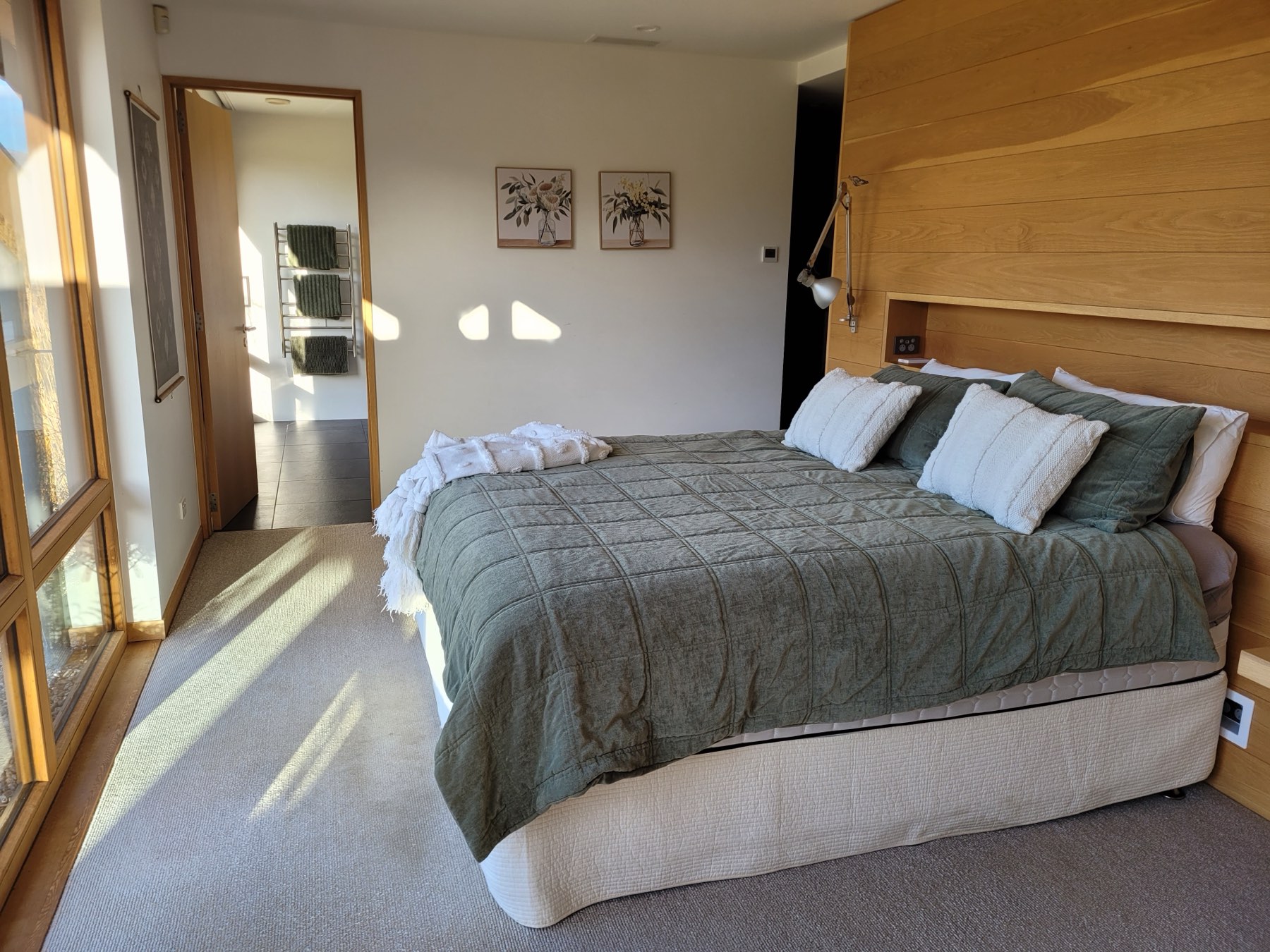 The main bedroom with a timber headboard and morning light
