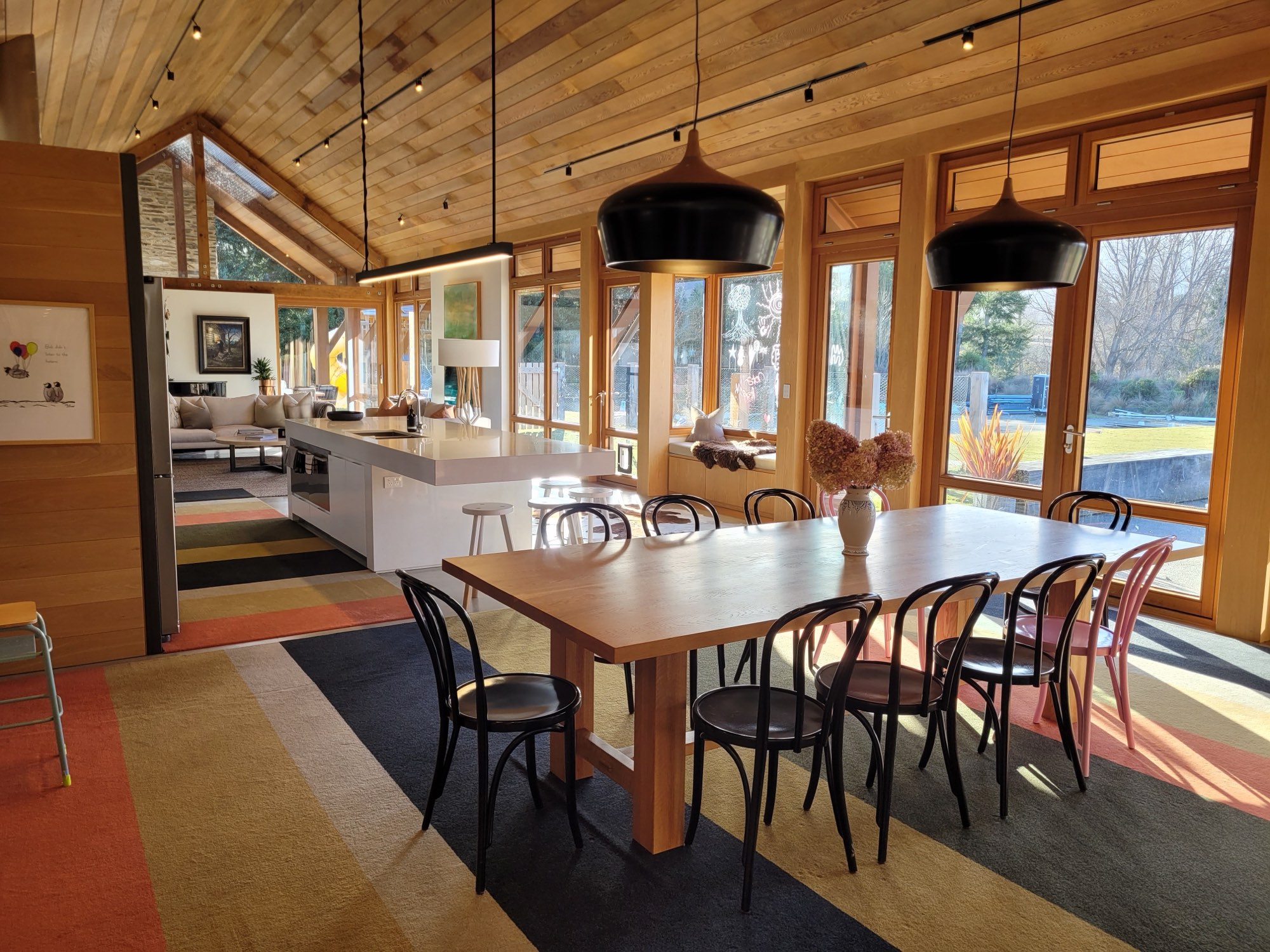 The dining table and kitchen beneath the timber ceiling
