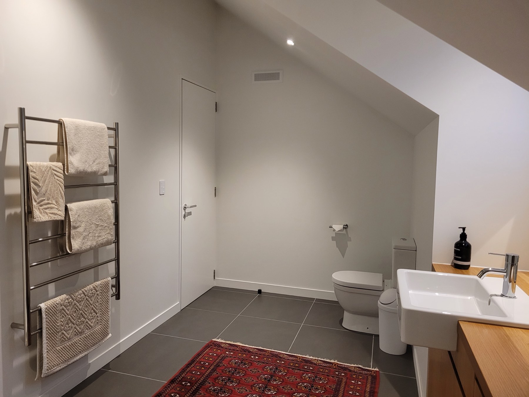 The loft bathroom, with a timber vanity and heated rail