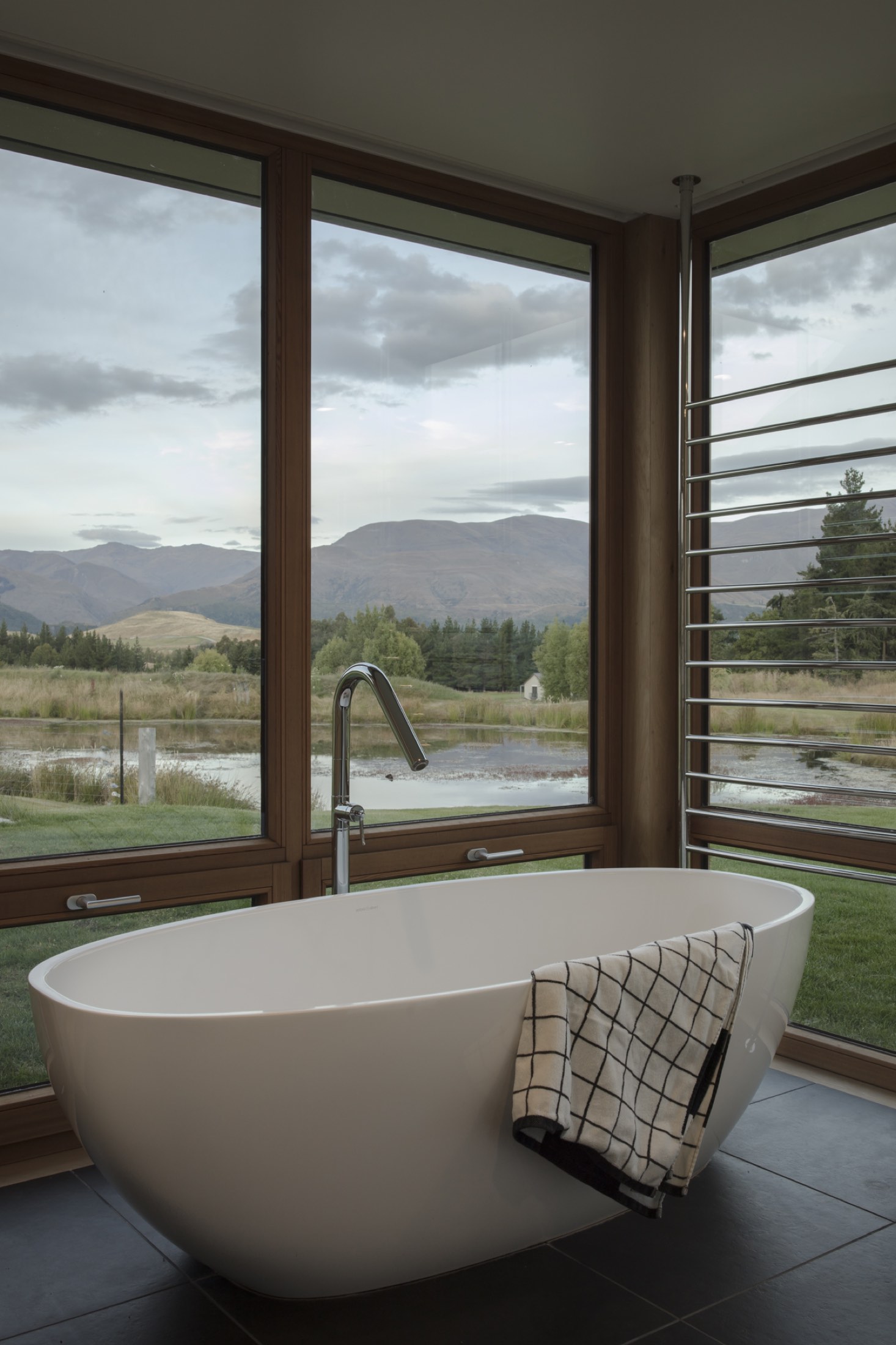 The bath, set to the view, with the pond and the mountains beyond