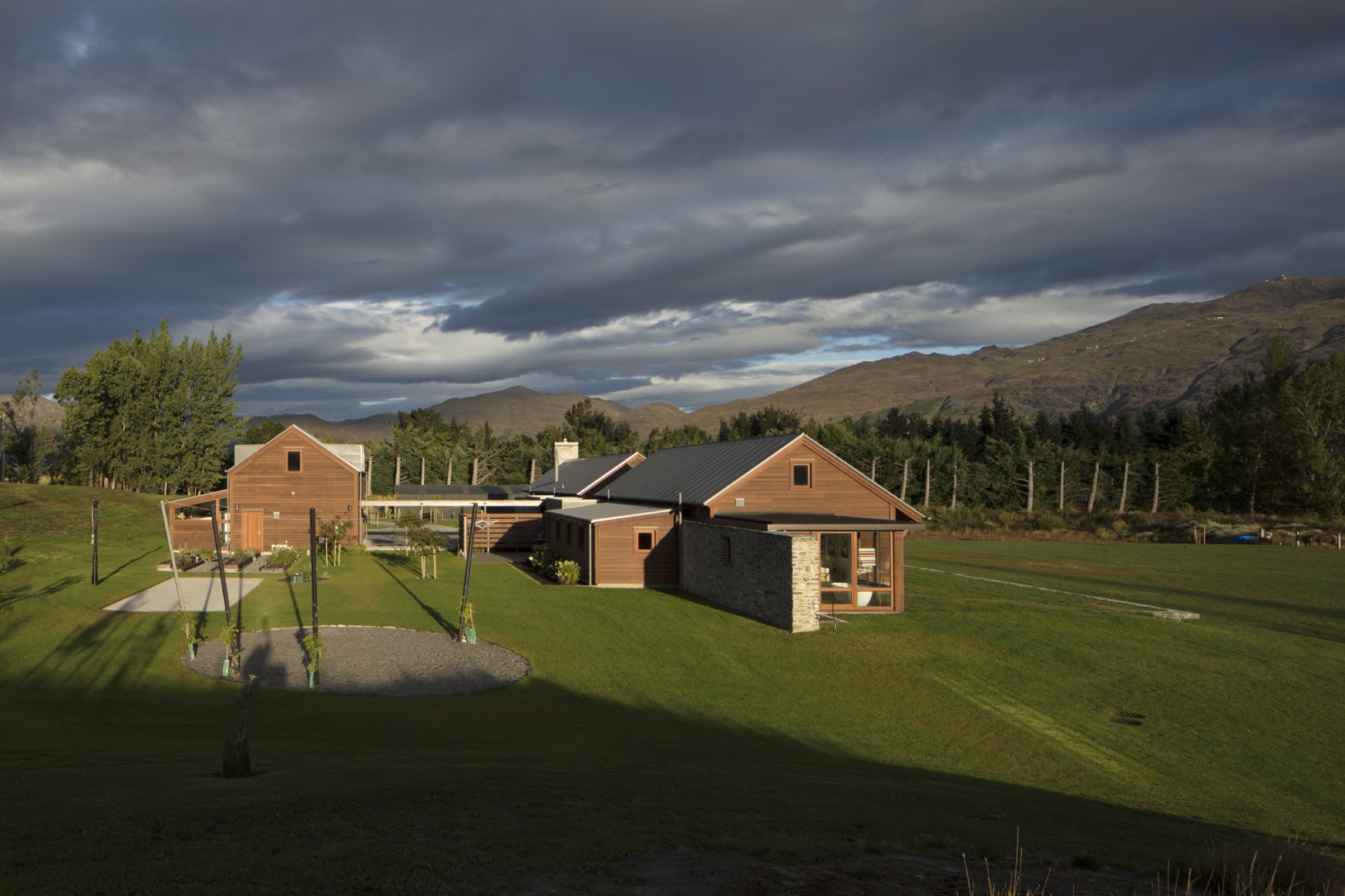 The homestead and the barn in late afternoon light, under the hill